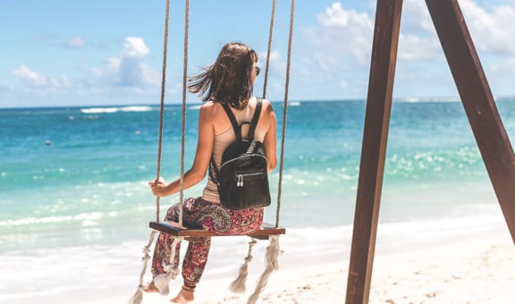 Giovane donna in altalena su una spiaggia