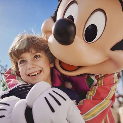 Bambino abbracciato ad un figurante con maschera di Topolino