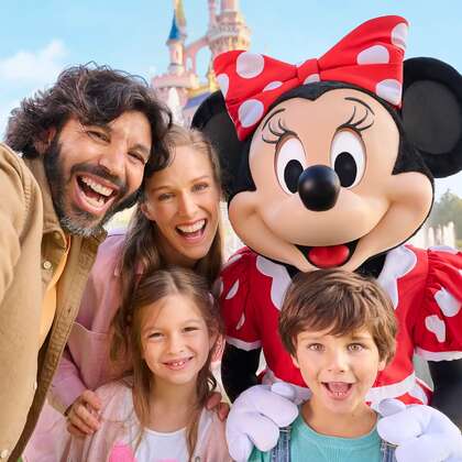 Selfie di una famiglia sorridente con una figurante vestita da Minnie